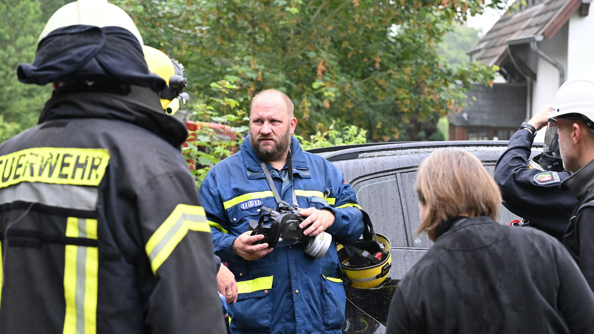 Einsatzkräfte von Feuerwehr, THW und Polizei besprechen das weitere Vorgehen an dem Haus in Bad Münstereifel-Holzem.