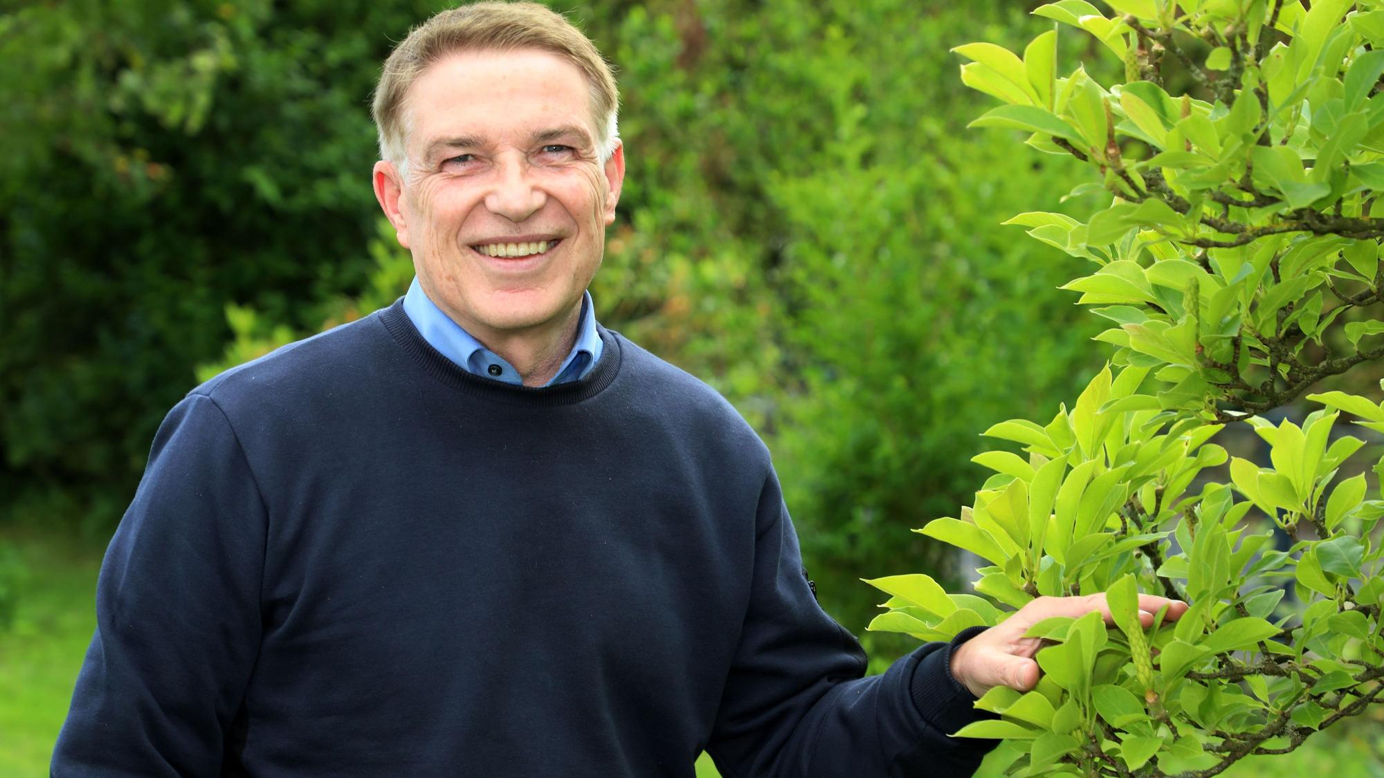 Der langjährige Kreisdirektor des Rheinisch-Bergischen Kreises, Dr. Erik Werdel, steht an einem Baum im Garten seines Hauses in Overath-Heiligenhaus.