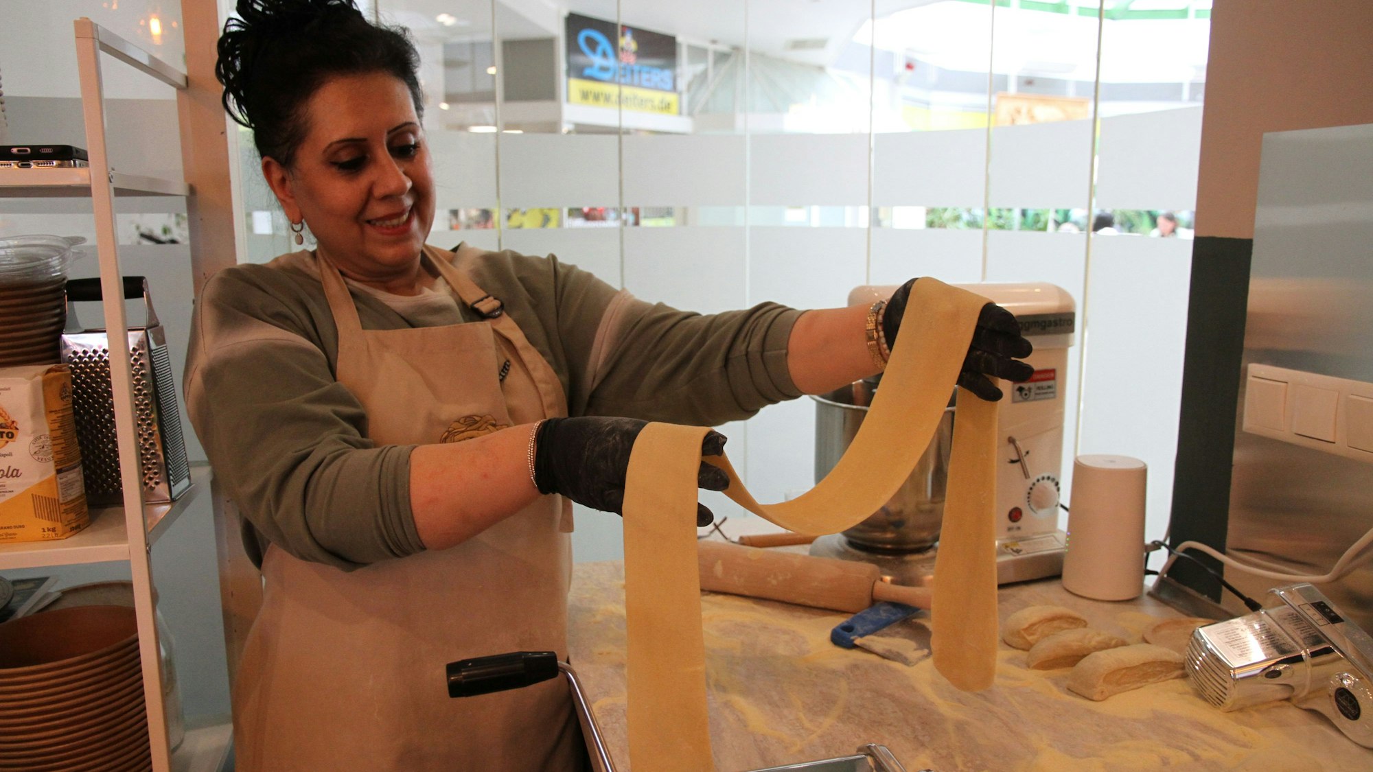 Eine Frau hält ein Band aus Pastateig in den Händen