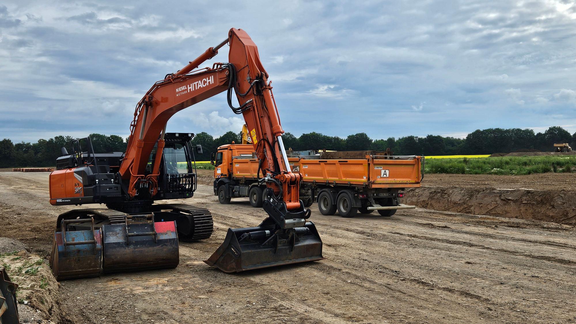 Ein Bagger und ein Lastwagen stehen auf einer Baustelle.