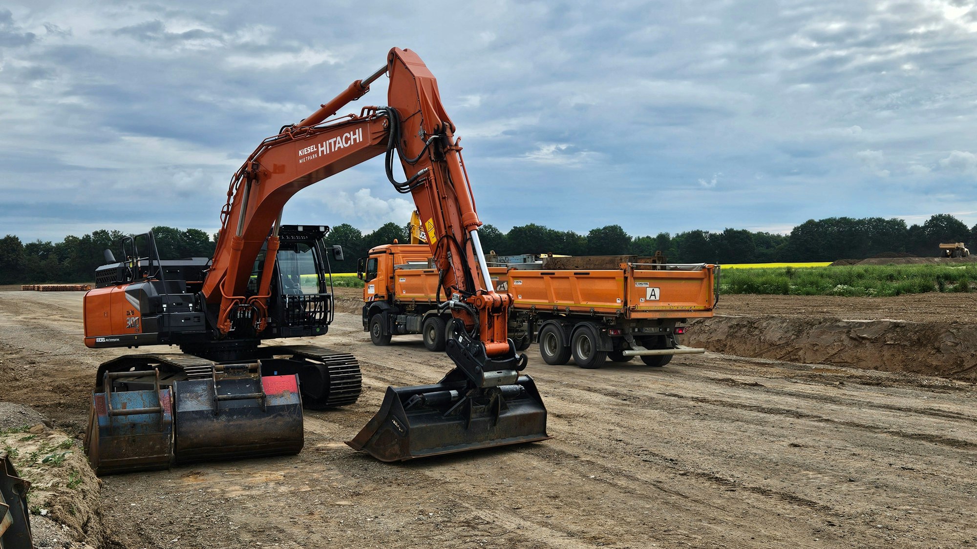 Ein Bagger und ein Lastwagen stehen auf einer Baustelle.