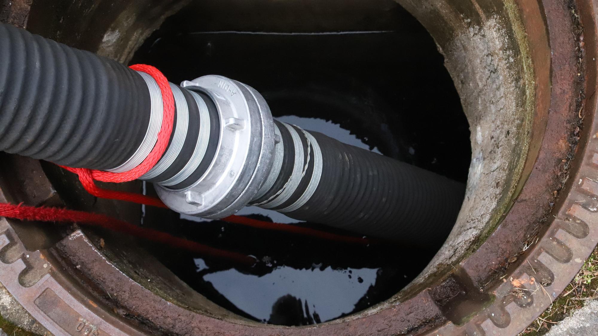Mit einer Schlauchleitung wird Löschwasser aus einer Zisterne gepumpt.