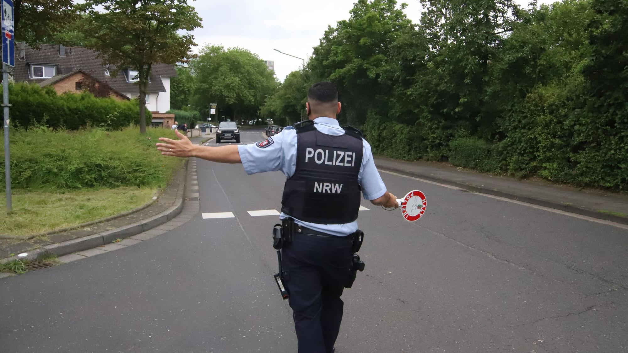Ein Polizist mit einer Kelle in der Hand winkt einen Autofahrer heraus.