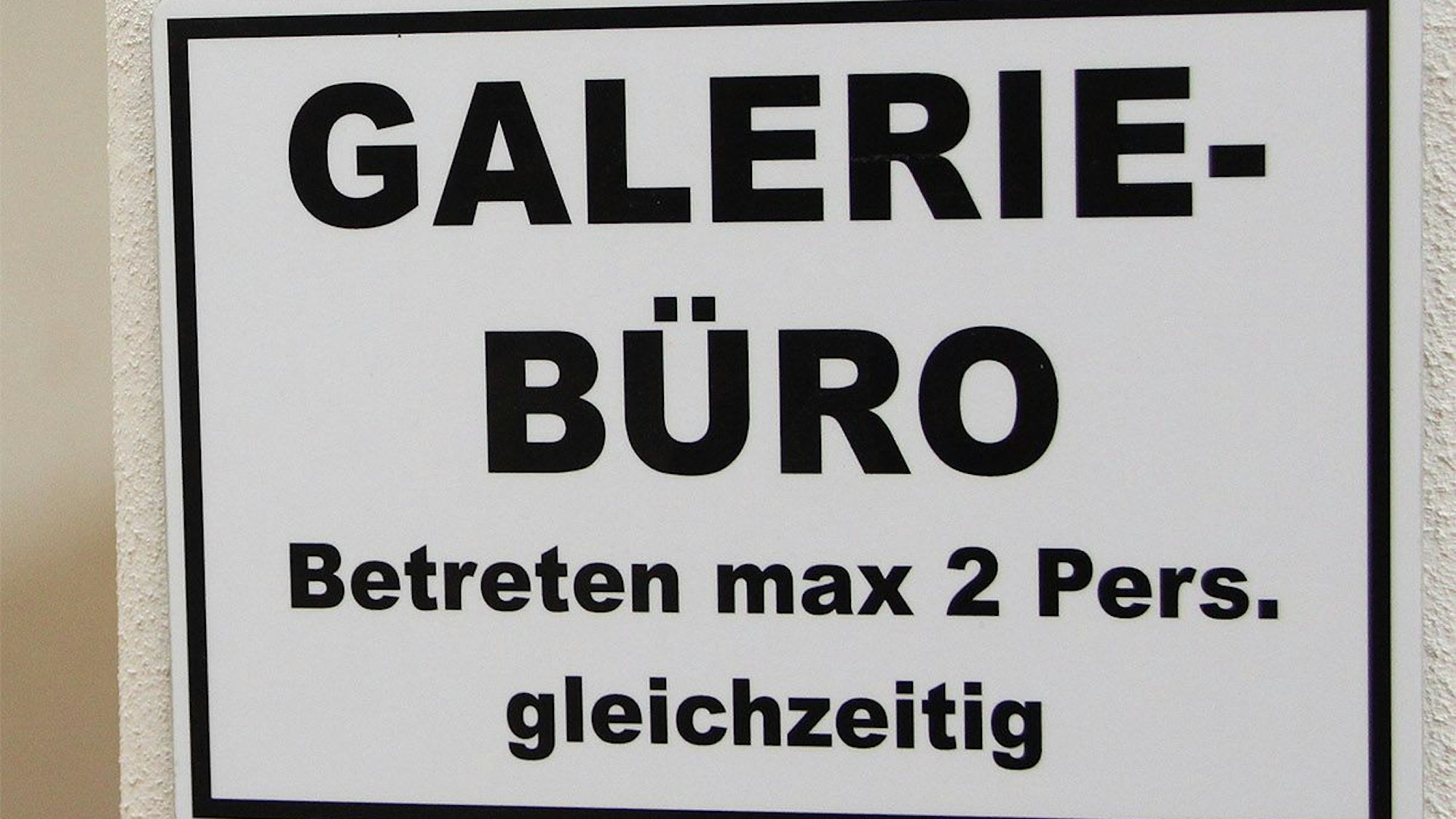 Auf einem Schild steht: „Galerie-Büro – Betreten max 2 Pers. gleichzeitig“