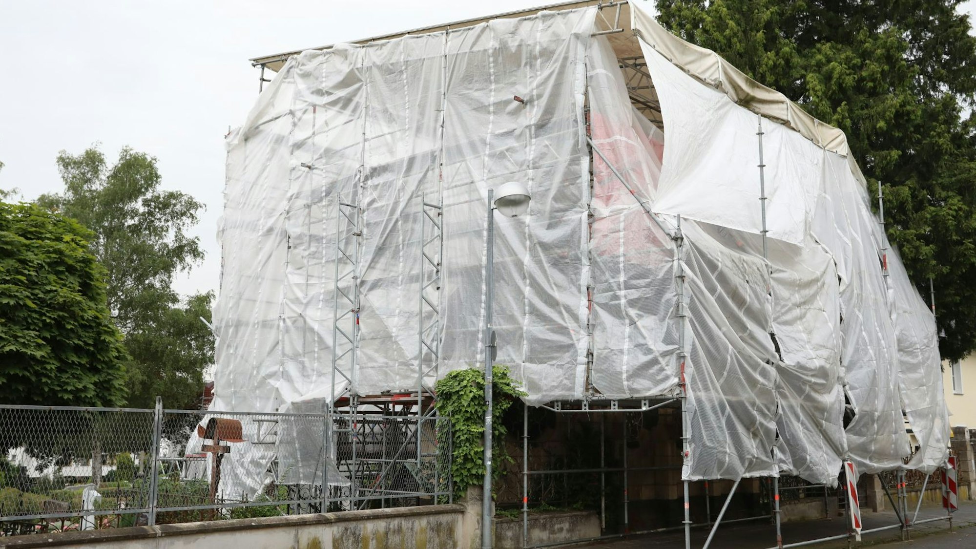 Ein Gebäude ist nahezu komplett unter weißen Planen verborgen, die an einem Gerüst befestigt sind.