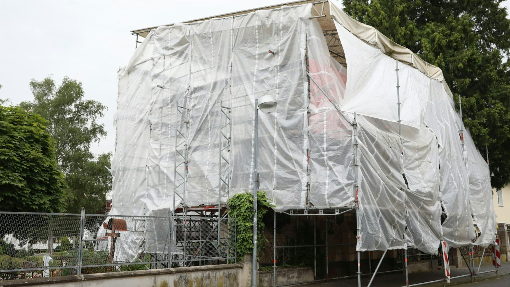 Ein Gebäude ist nahezu komplett unter weißen Planen verborgen, die an einem Gerüst befestigt sind.