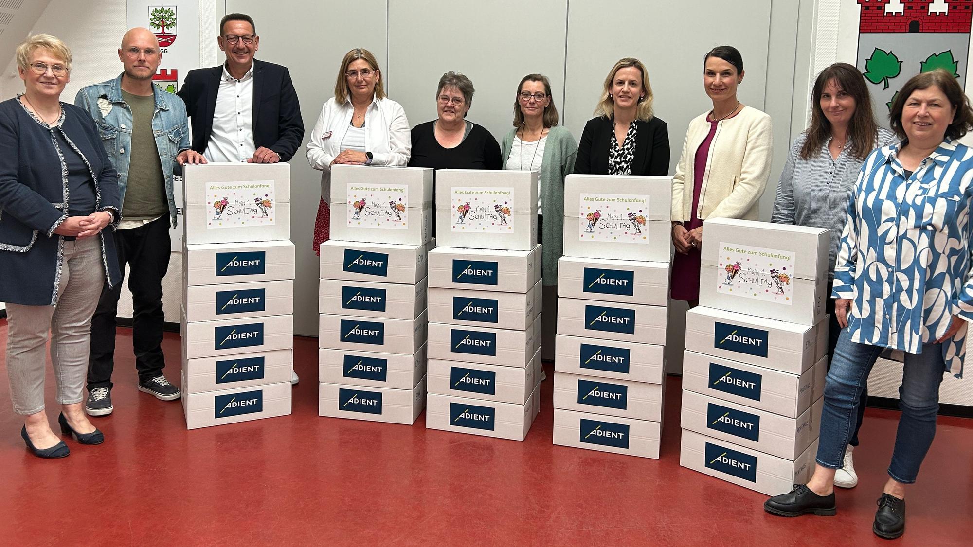 Bürgermeister Runge, Vertreter von Adient und von Kitas stehen mit Paketen im Sitzungssaal des Burscheider Rathauses.