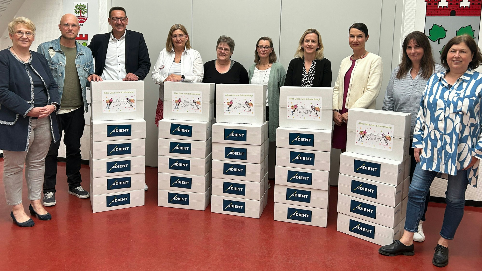 Bürgermeister Runge, Vertreter von Adient und von Kitas stehen mit Paketen im Sitzungssaal des Burscheider Rathauses.