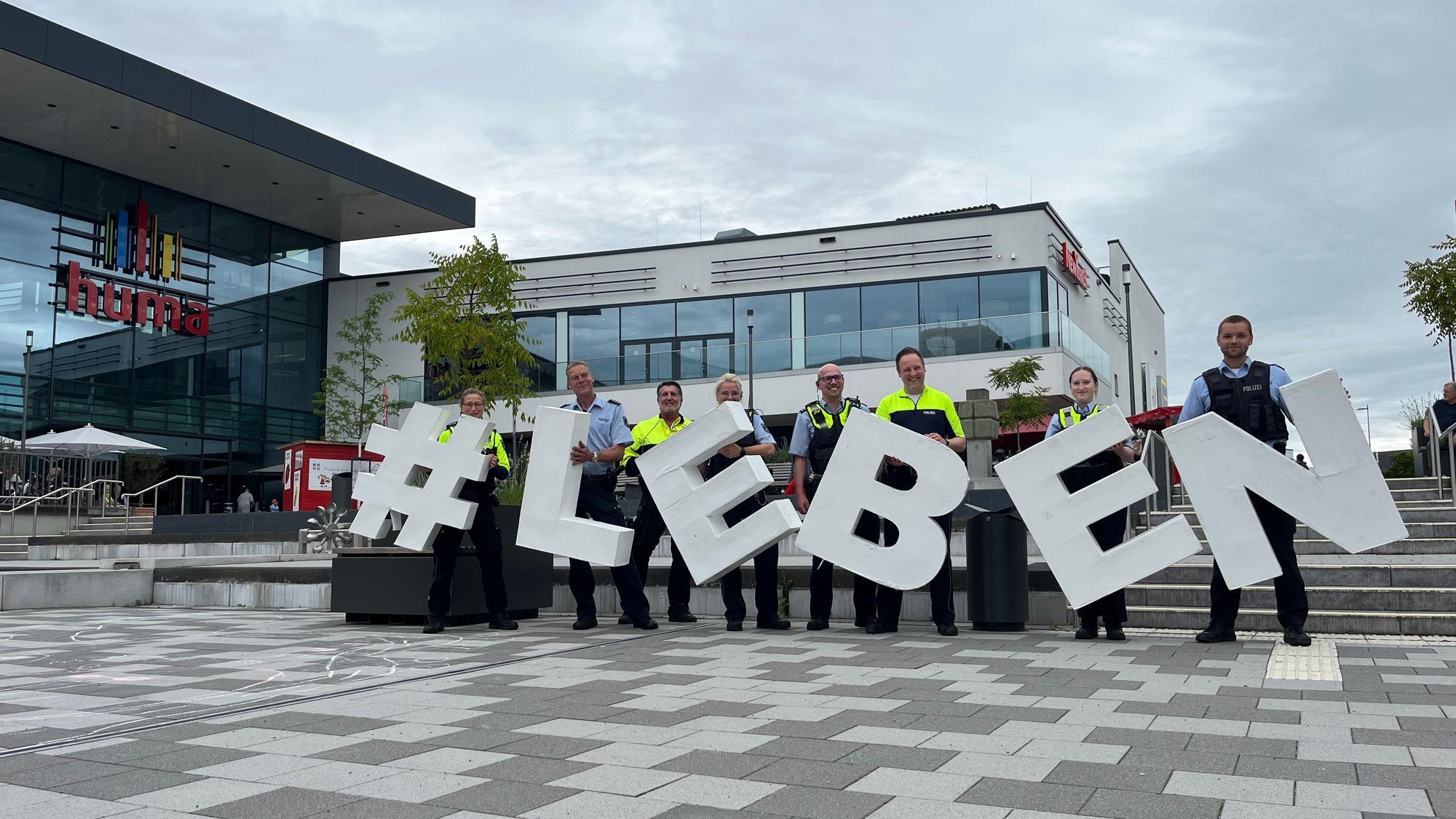 Polizisten zeigen das Motto der Fachstrategie in die Höhe, # Leben