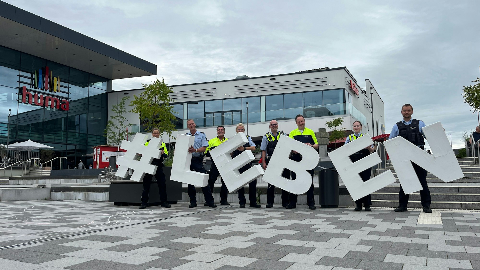 Polizisten zeigen das Motto der Fachstrategie in die Höhe, # Leben