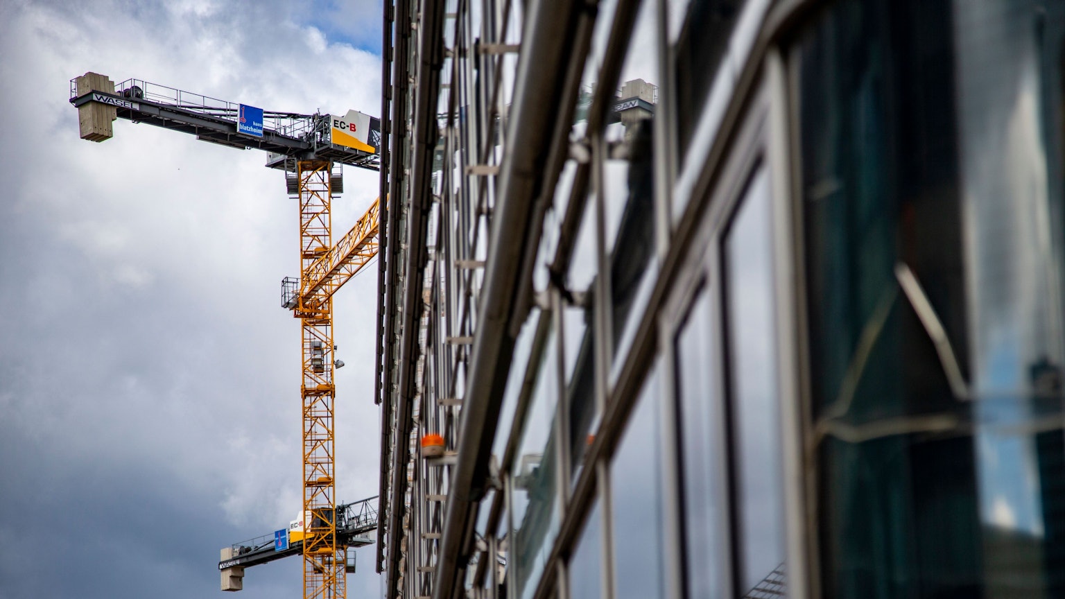 Ein Baukran steht vor der Fassade eines Büro-Neubaus.