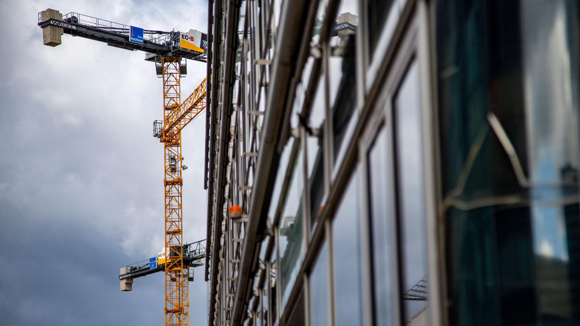 Ein Baukran steht vor der Fassade eines Büro-Neubaus.