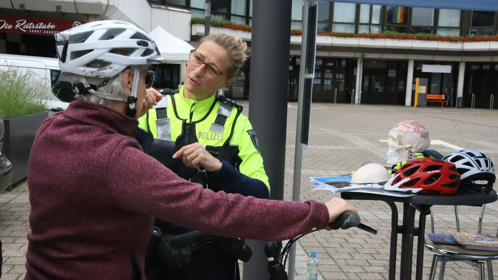 Eine Polizistin zeigt einer Frau, wie der Helm angepasst werden kann.