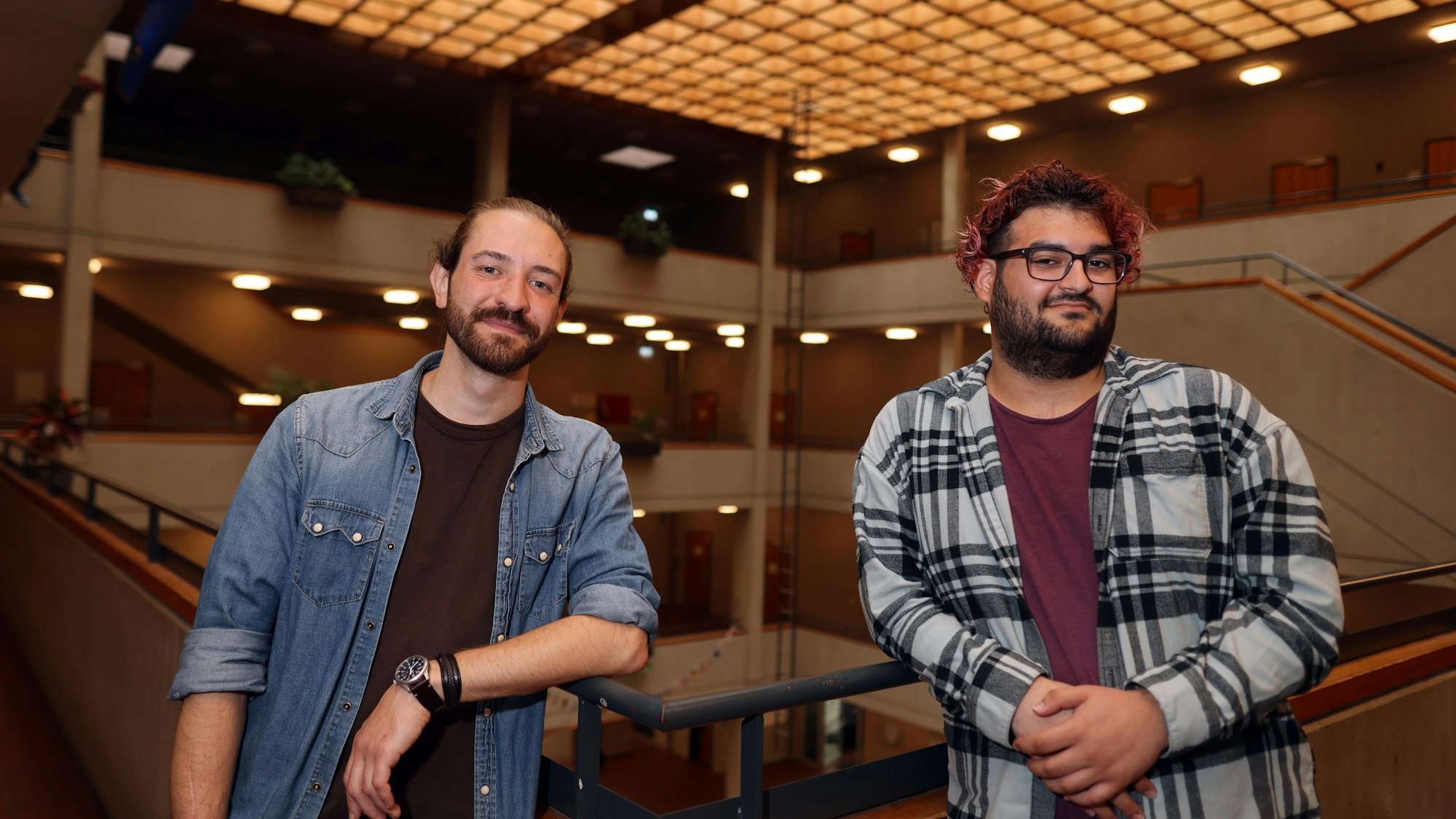 Zwei junge Männer stehen im Atrium des Köln-Kollegs.
