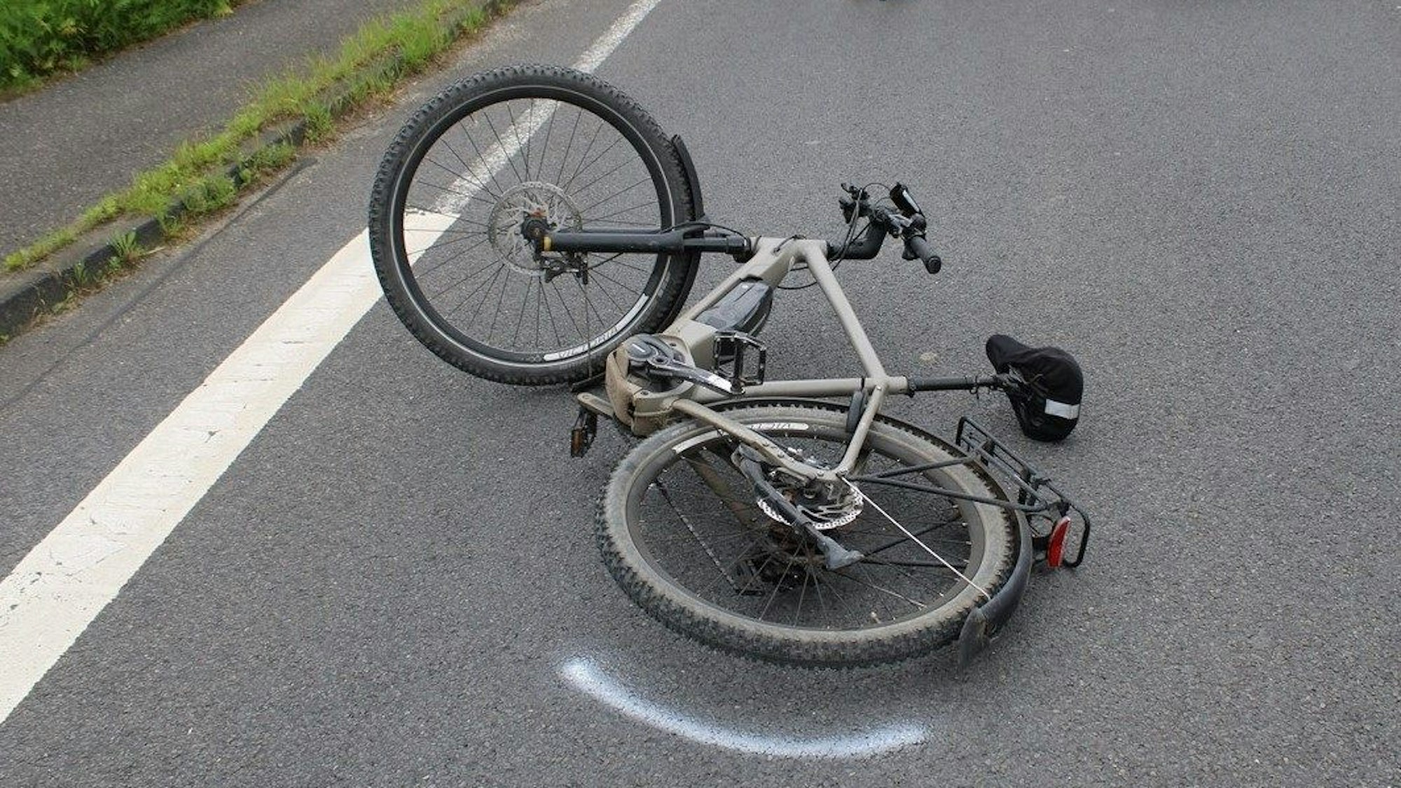 Ein in einen Unfall verwickeltes Pedelec liegt auf der Straße, daneben ist eine Polizeimarkierung.