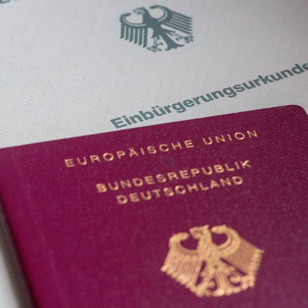 Eine Einbürgerungsurkunde der Bundesrepublik Deutschland und ein deutscher Reisepass liegen auf einem Tisch.