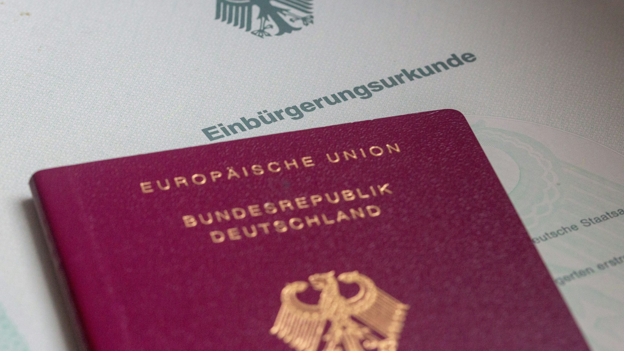 Eine Einbürgerungsurkunde der Bundesrepublik Deutschland und ein deutscher Reisepass liegen auf einem Tisch.