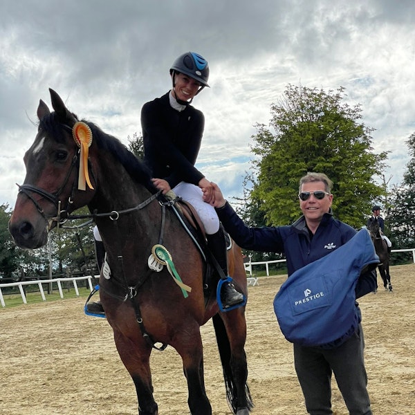 Die Siegerin eines Reitwettbewerbs sitz noch auf dem Pferd und bekommt ihren Preis vom Sponsor überreicht.