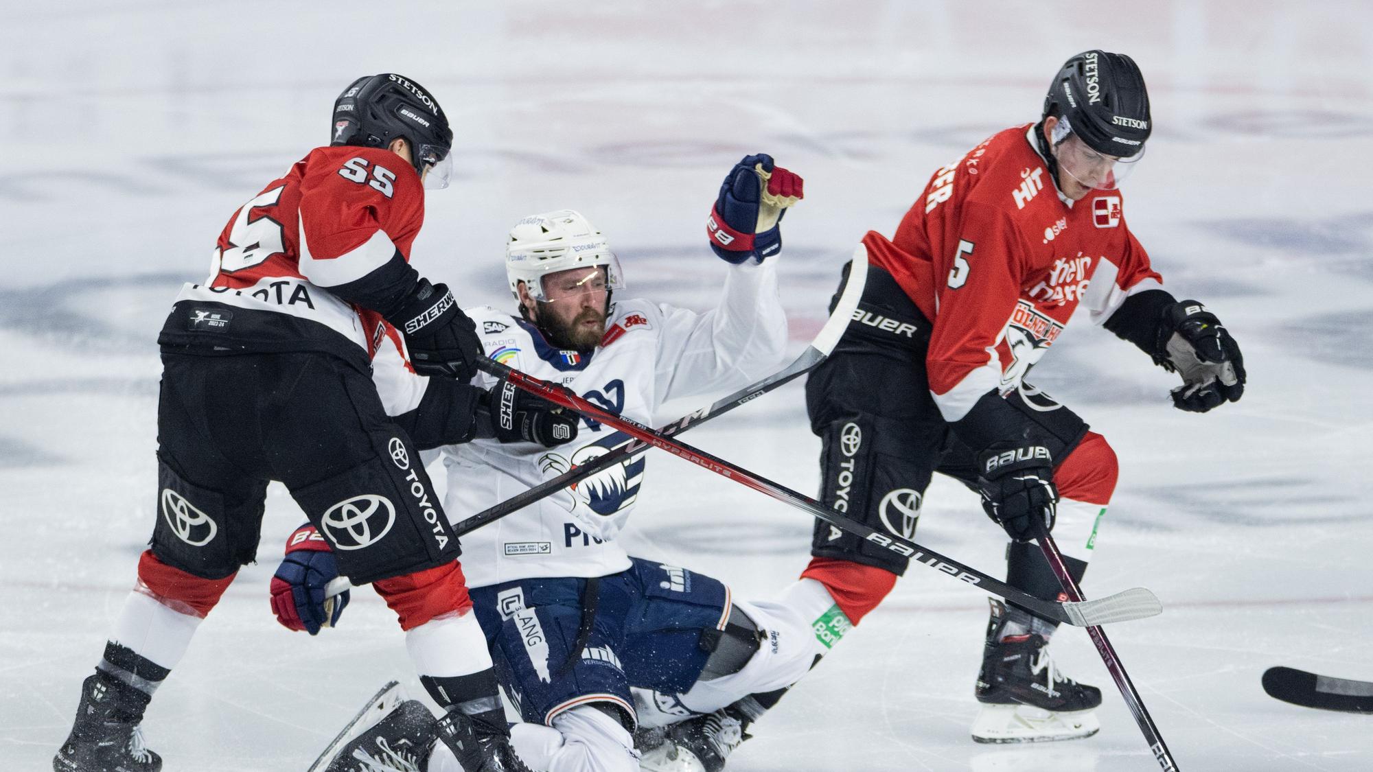 Eishockey: DEL, Kölner Haie - Adler Mannheim, Hauptrunde, 52. Spieltag, Lanxess Arena. Kölns Carter Proft (l) sowie Robin van Calster (r) und Mannheims Keaton Thompson versuchen an den Puck zu kommen.