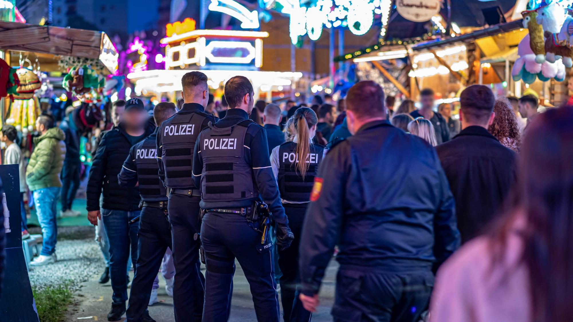 Polizeibeamte gehen über das Kirmesgelände Hohen Steinert.