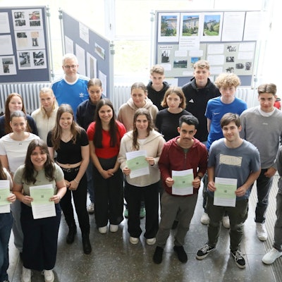 Eine Gruppe von Schülerinnen und Schülern steht vor den Stellwänden einer Ausstellung.