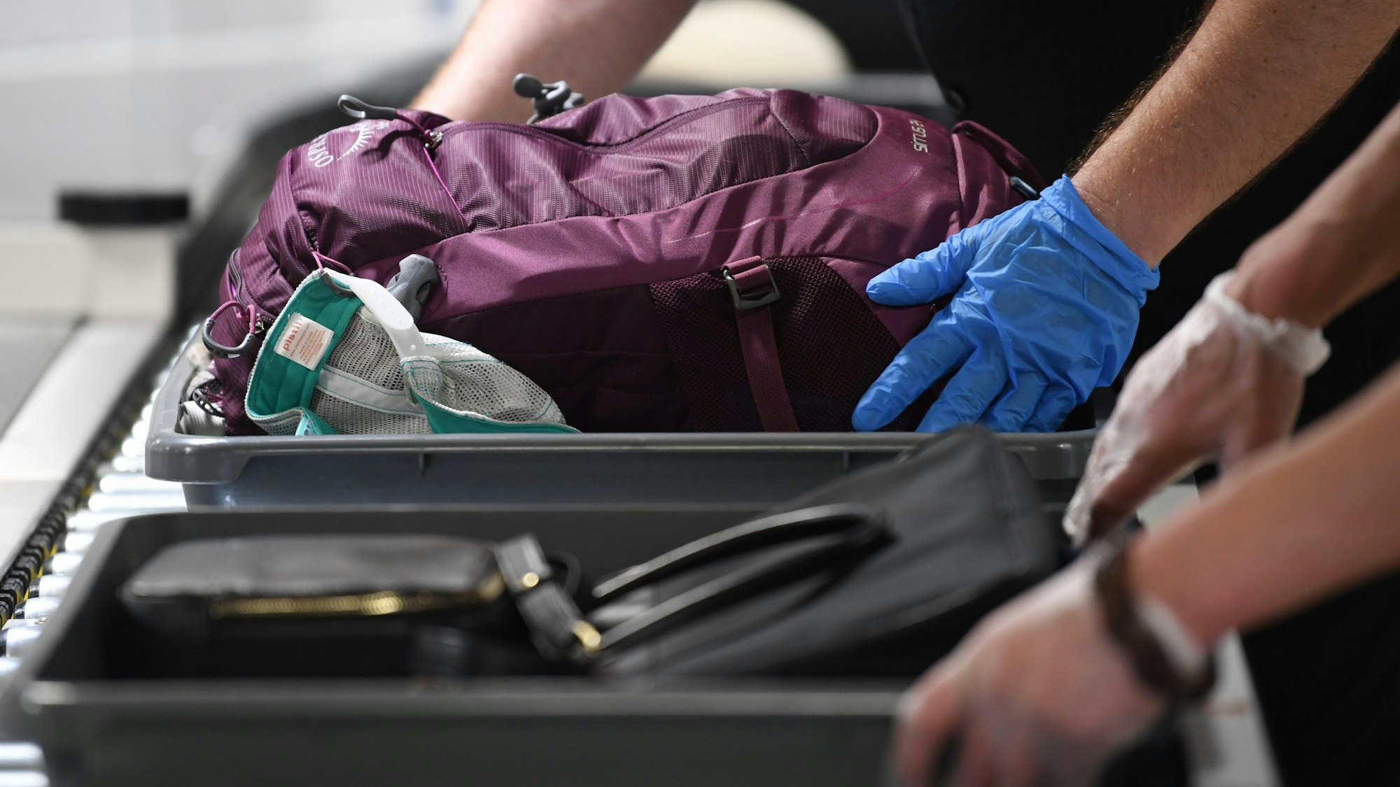 Das Handgepäck von Flugreisenden wird in Plastikwannen abgelegt.