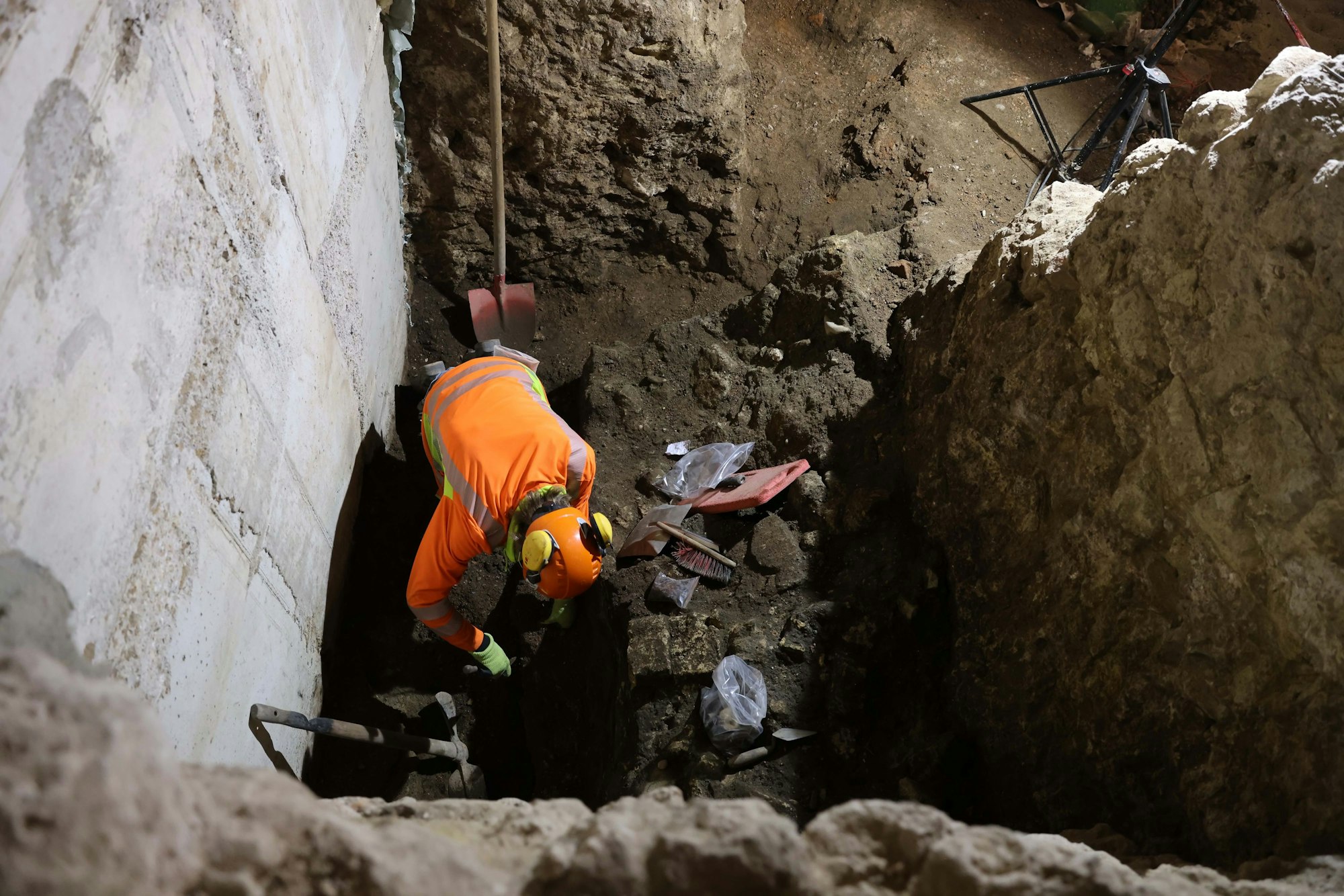 Ein Mann kniet in einer Baugrube.