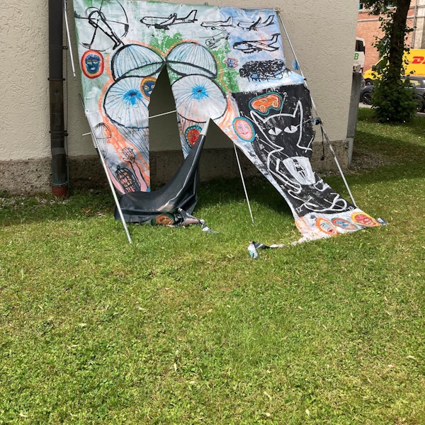 Ein zerschnittenes Bild lehnt an einer Hauswand.