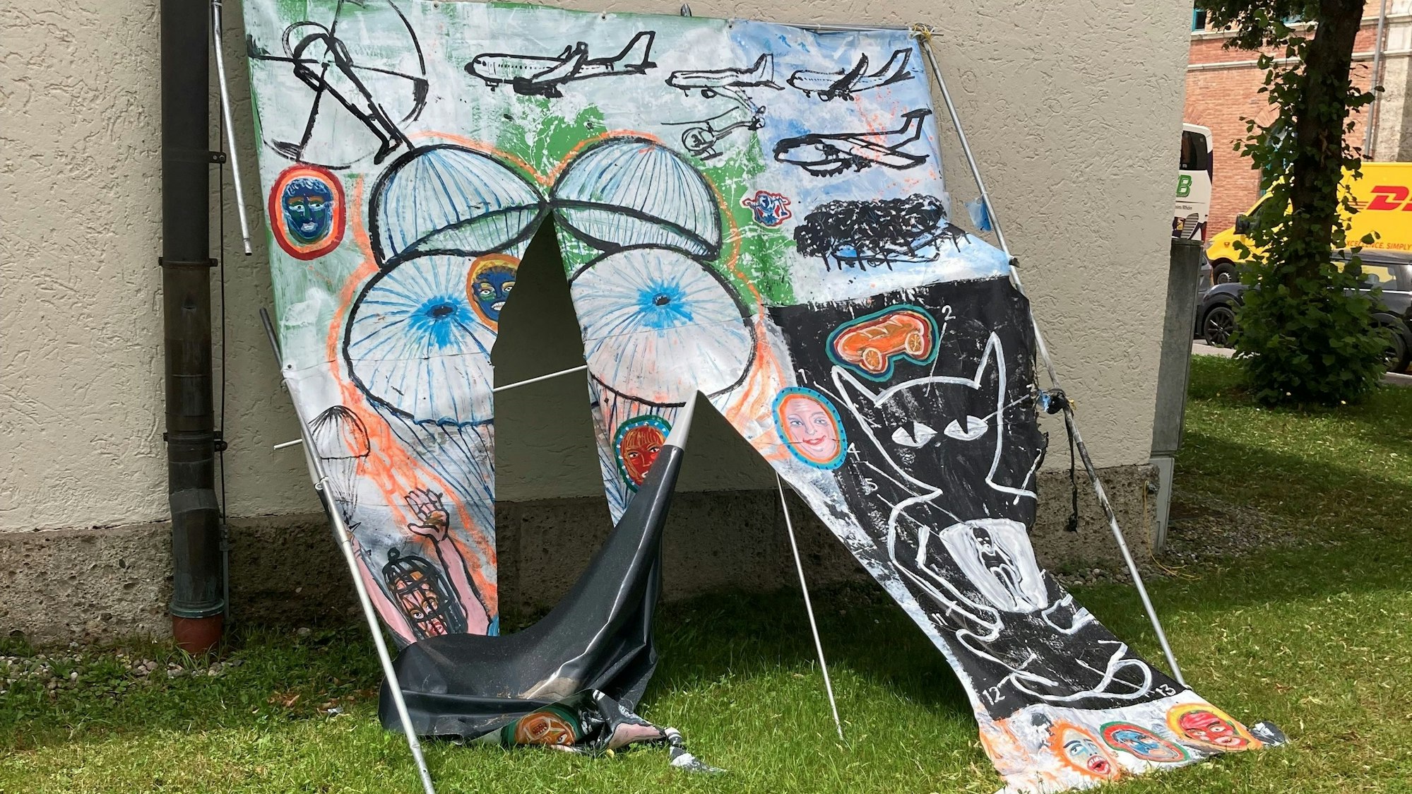 Ein zerschnittenes Bild lehnt an einer Hauswand.