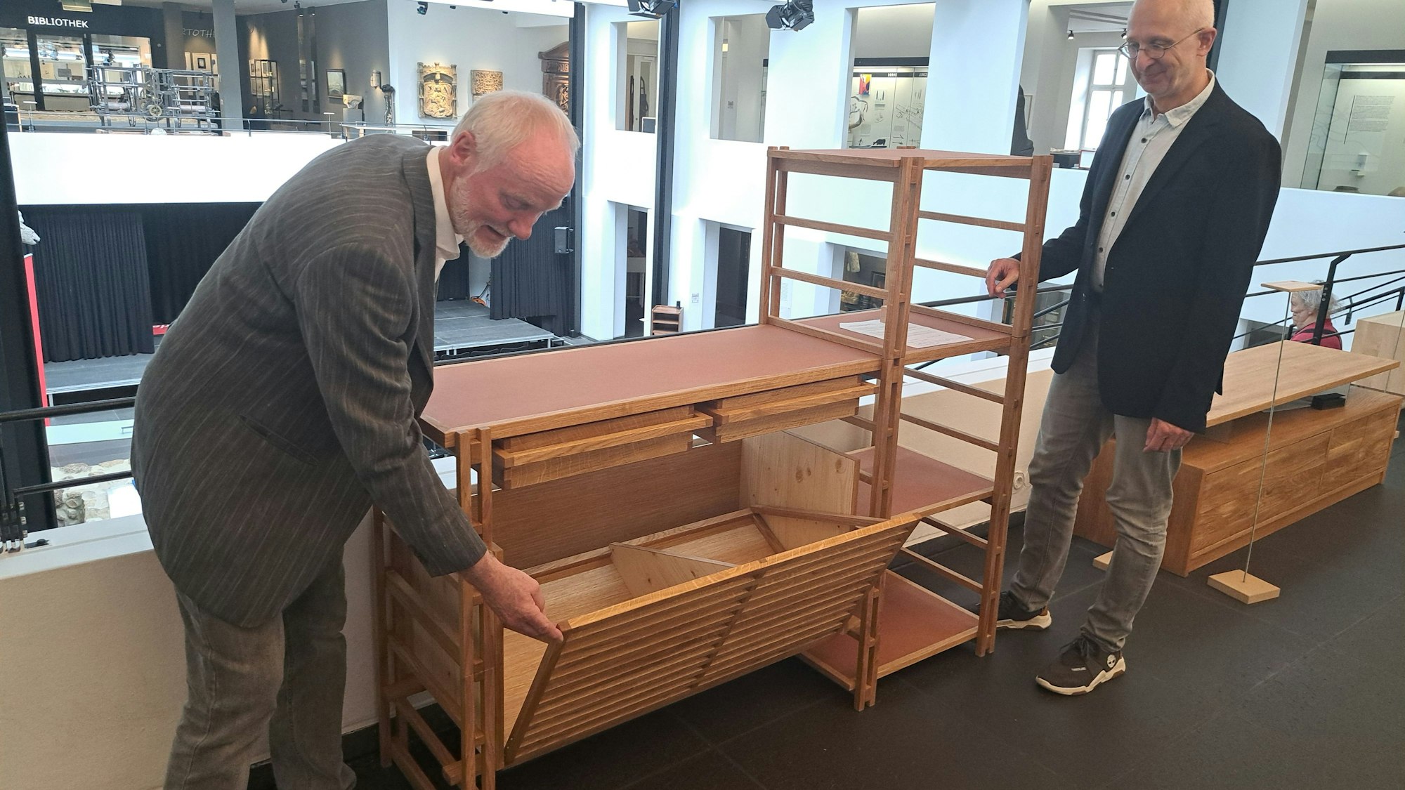 Geschäftsführer Wolfgang Schmeil (r.) und Obermeister Wilhelm Gießelbach von der Tischler-Innung Bonn/Rhein-Sieg präsentieren eines der beim Wettbewerb "Die gute Form" ausgezeichneten Gesellenstücke, ein Regalsystem von Franziska Schaletzki.