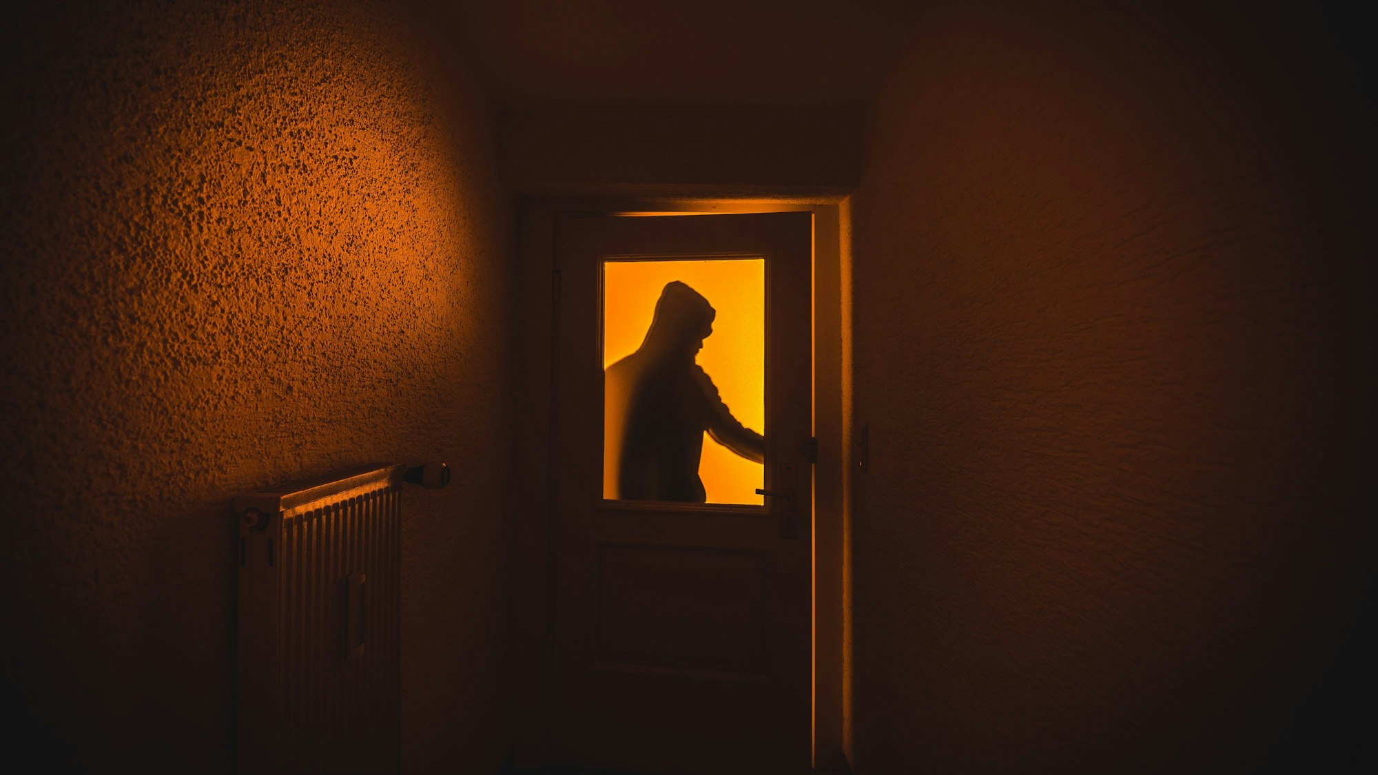 Ein Mann macht sich in der Dunkelheit an einer Tür zu schaffen.