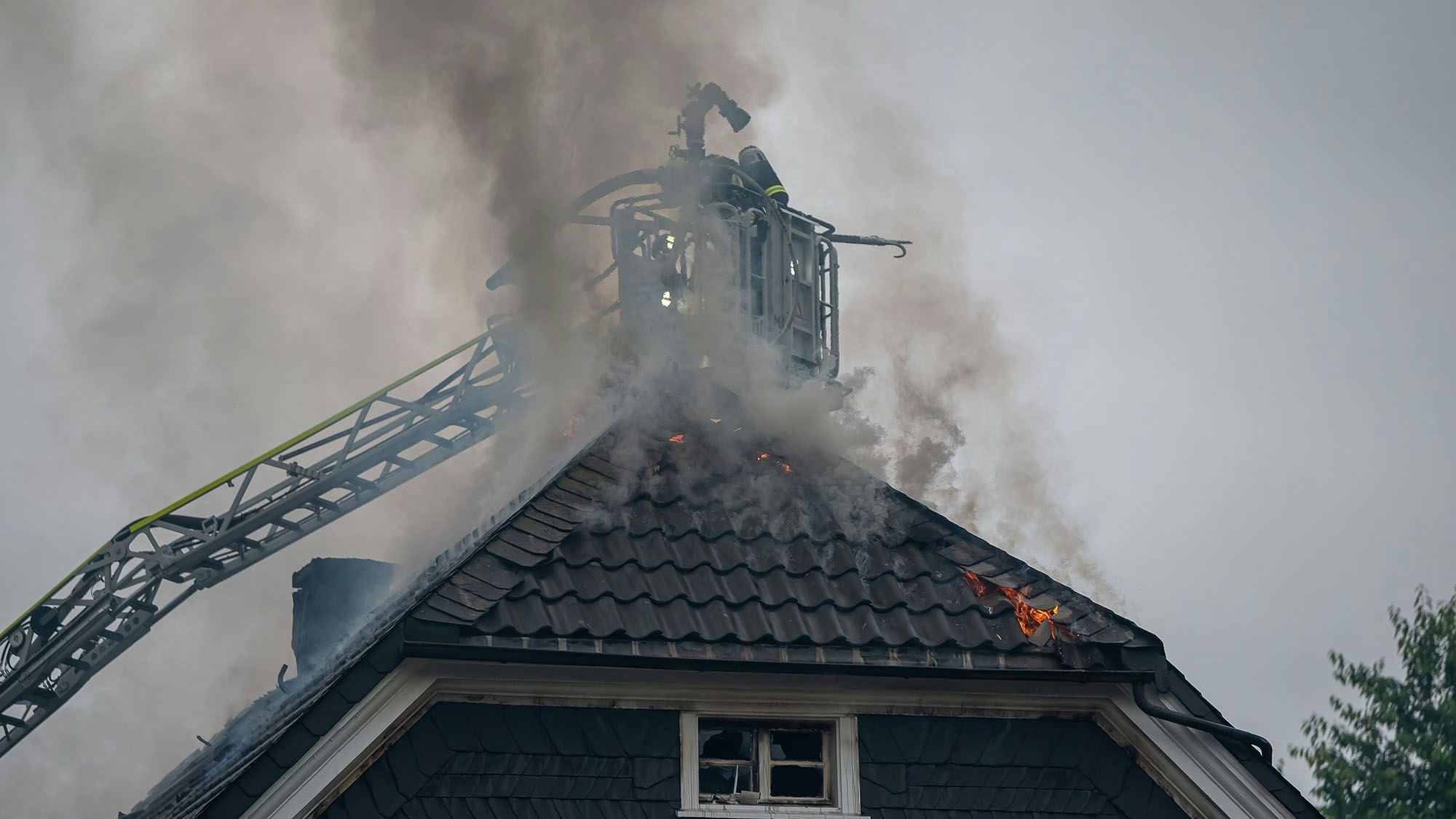 Von der Drehleiter aus bekämpfen Feuerwehrleute den Dachstuhlbrand in einem Mehrfamilienhaus in Gummersbach-Derschlag.