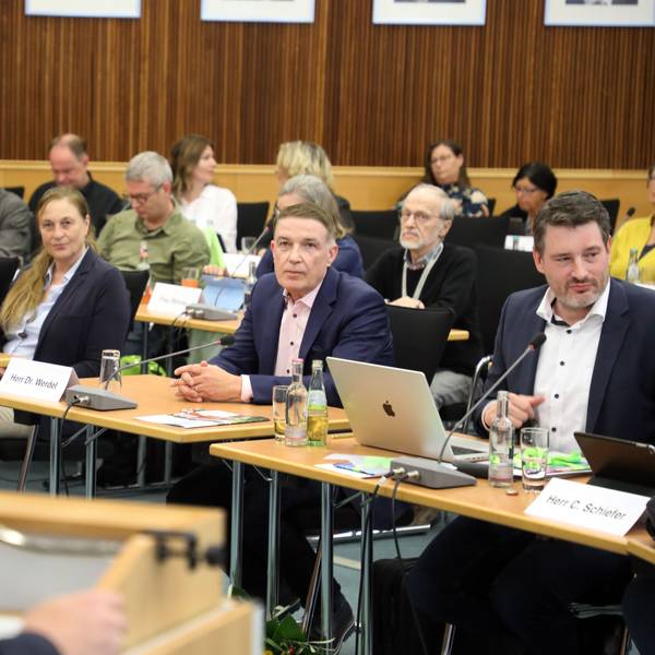 Ex-Kreisdirektor Dr. Erik Werdel sitzt zwischen Politikern im Kreistag, Landrat Stephan Santelmann spricht am Rednerpult.