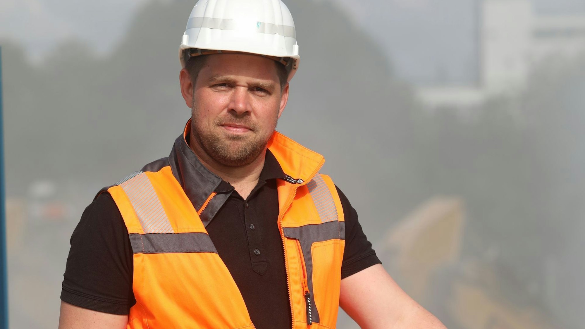 Ein Mann mit weißem Schutzhelm und orangefarbener Warnweste