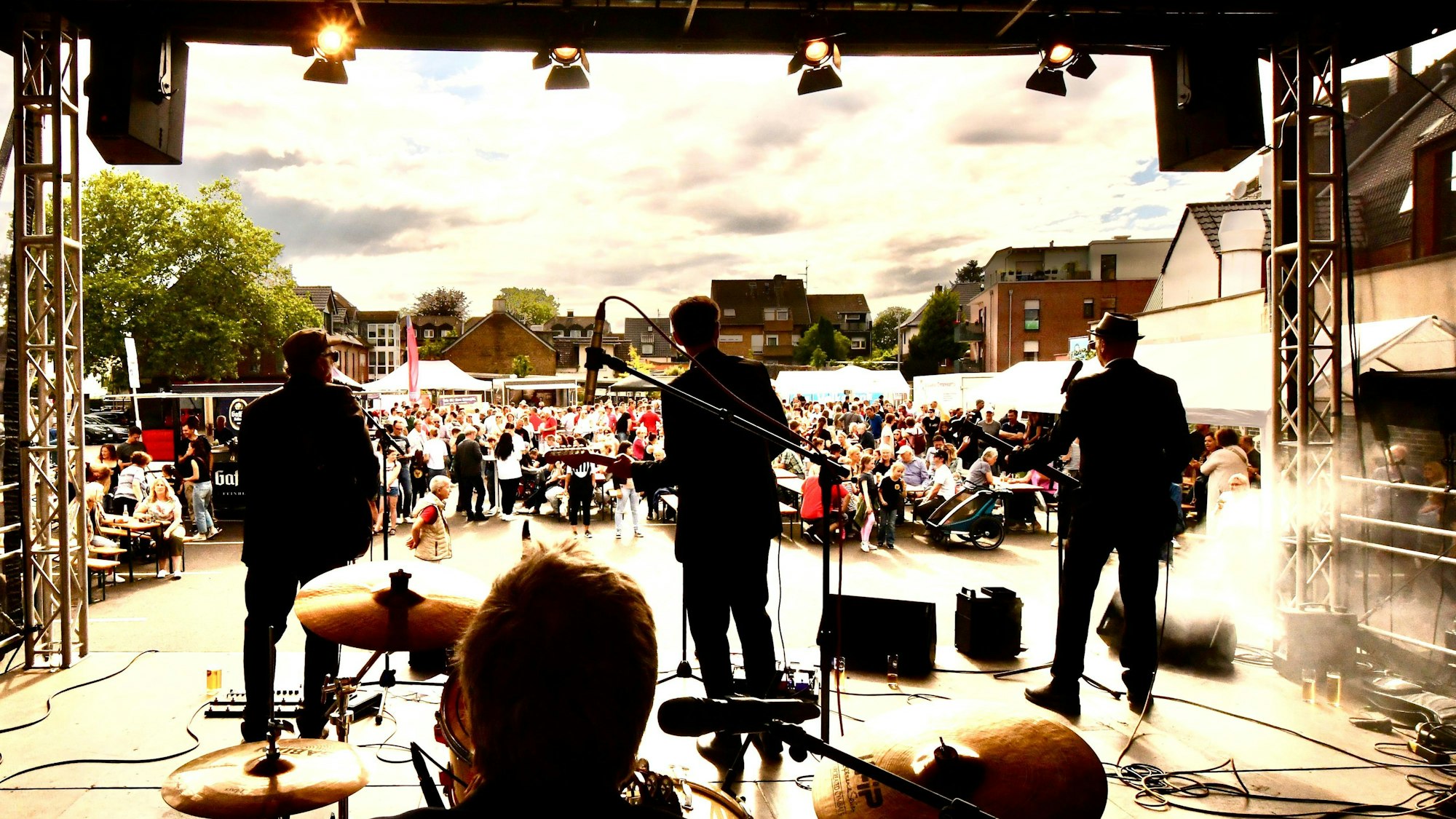 Zu sehen sind eine Band auf einer Bühne und im Hintergrund die Zuschauer.