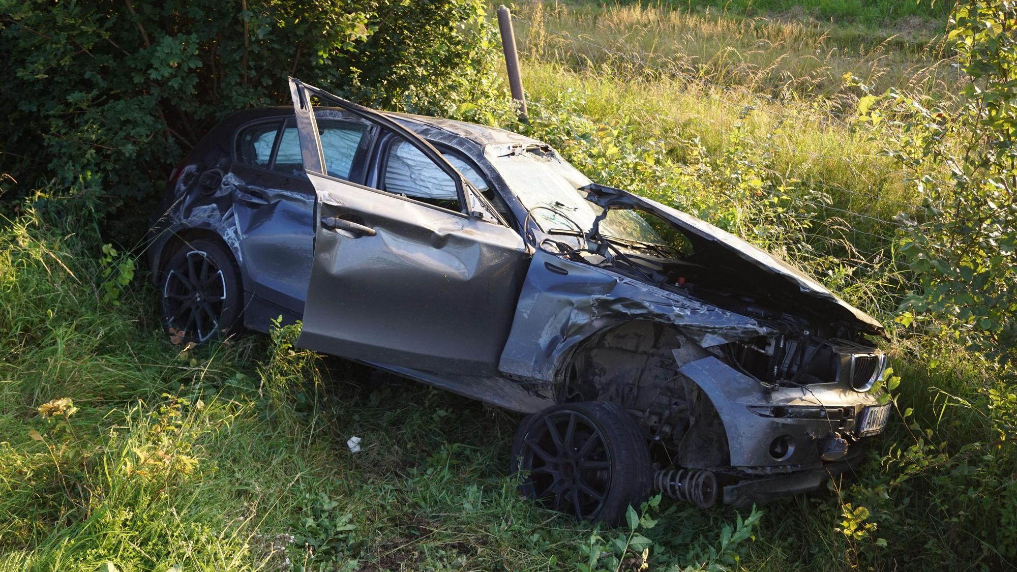 Ein zerbeultes graues Auto liegt in einem Straßengraben.