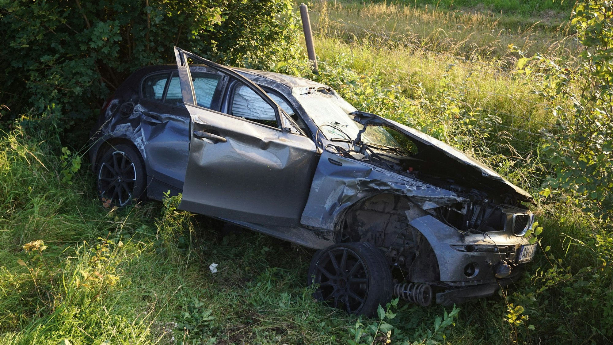 Ein zerbeultes graues Auto liegt in einem Straßengraben.