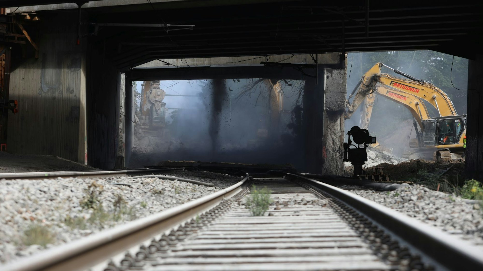 Blick auf Eisenbahngleise du eine Unterführung, rechts ein Bagger