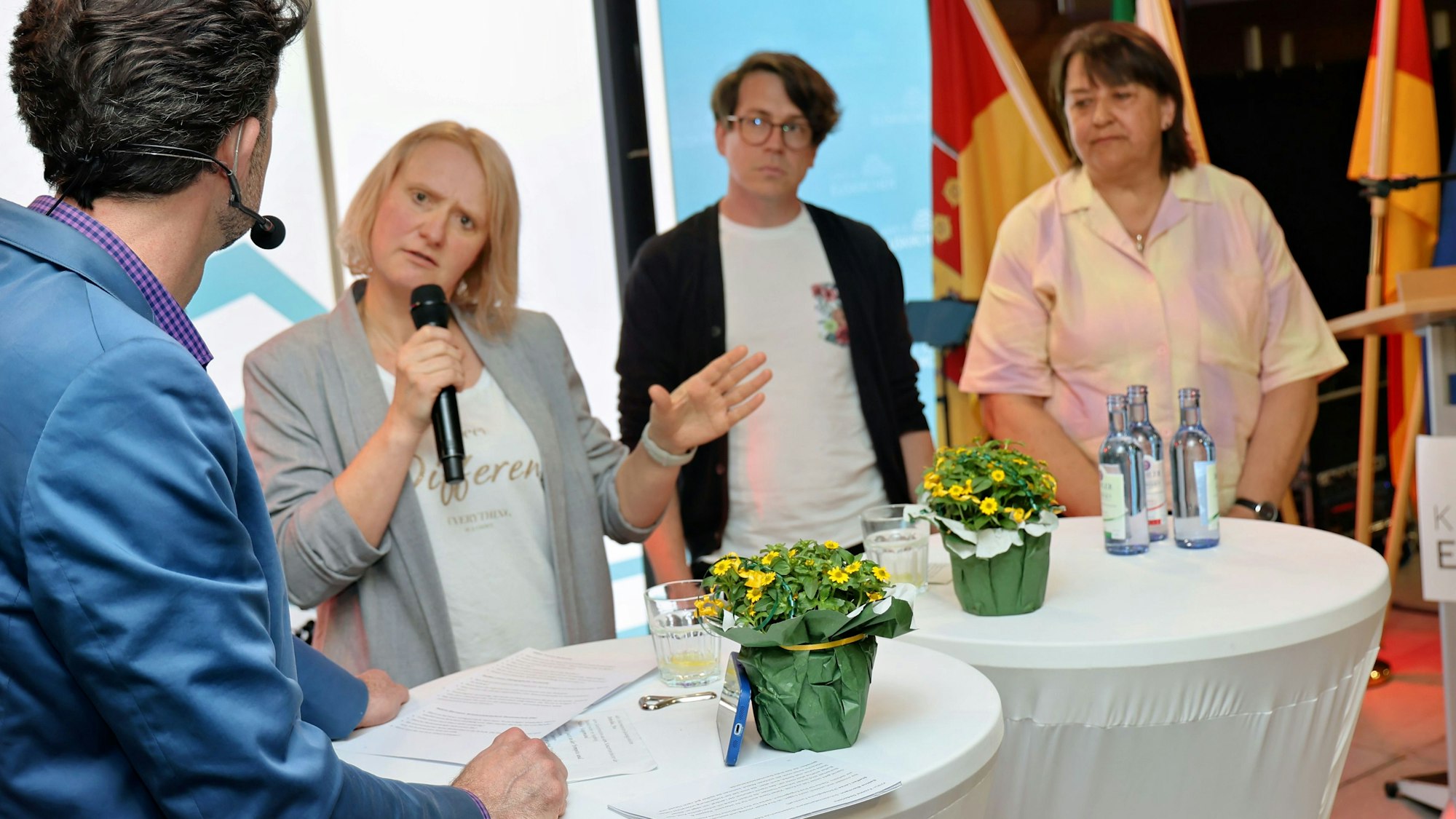 Yvonne Dederichs, Steffen Lenze und Sabine Biermann stehen an zwei Stehtischen und sprechen mit einem Moderator.