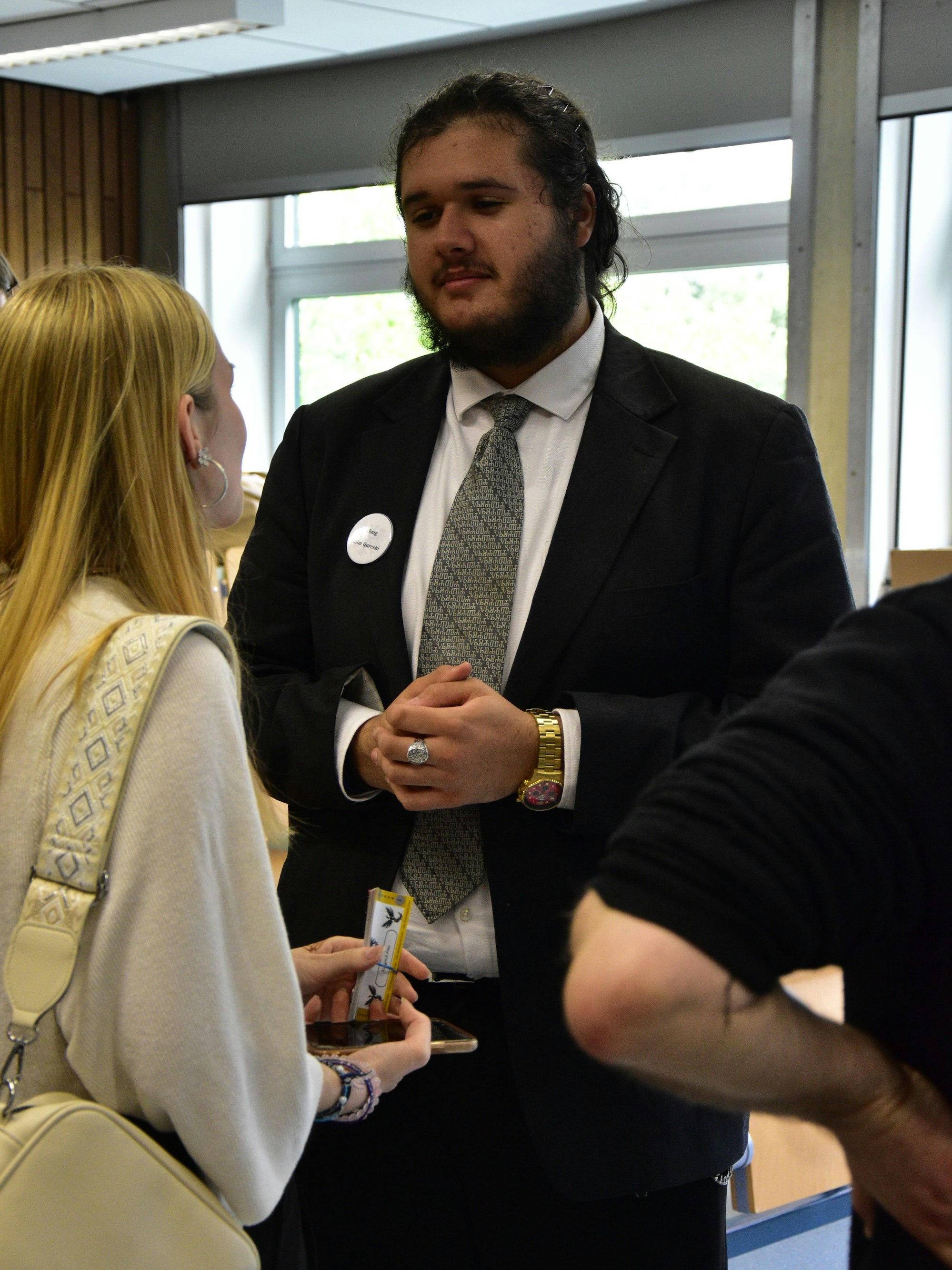 Ein großer Jugendlicher im Anzug und mit goldener Uhr.