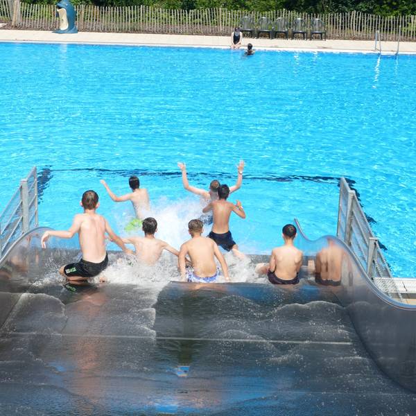 Jungen rutschen eine breite Wasserrutsche herunter.