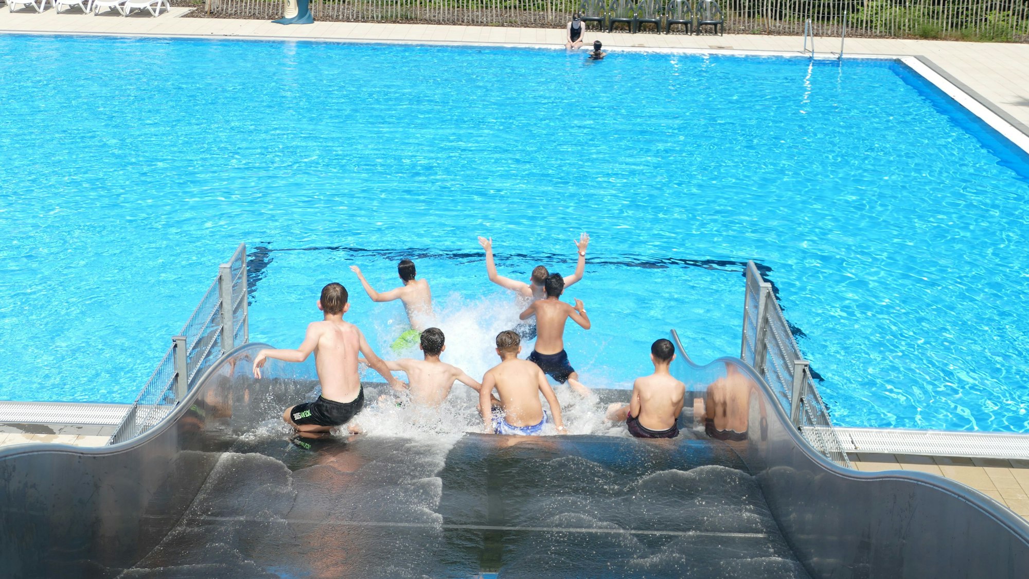 Jungen rutschen eine breite Wasserrutsche herunter.