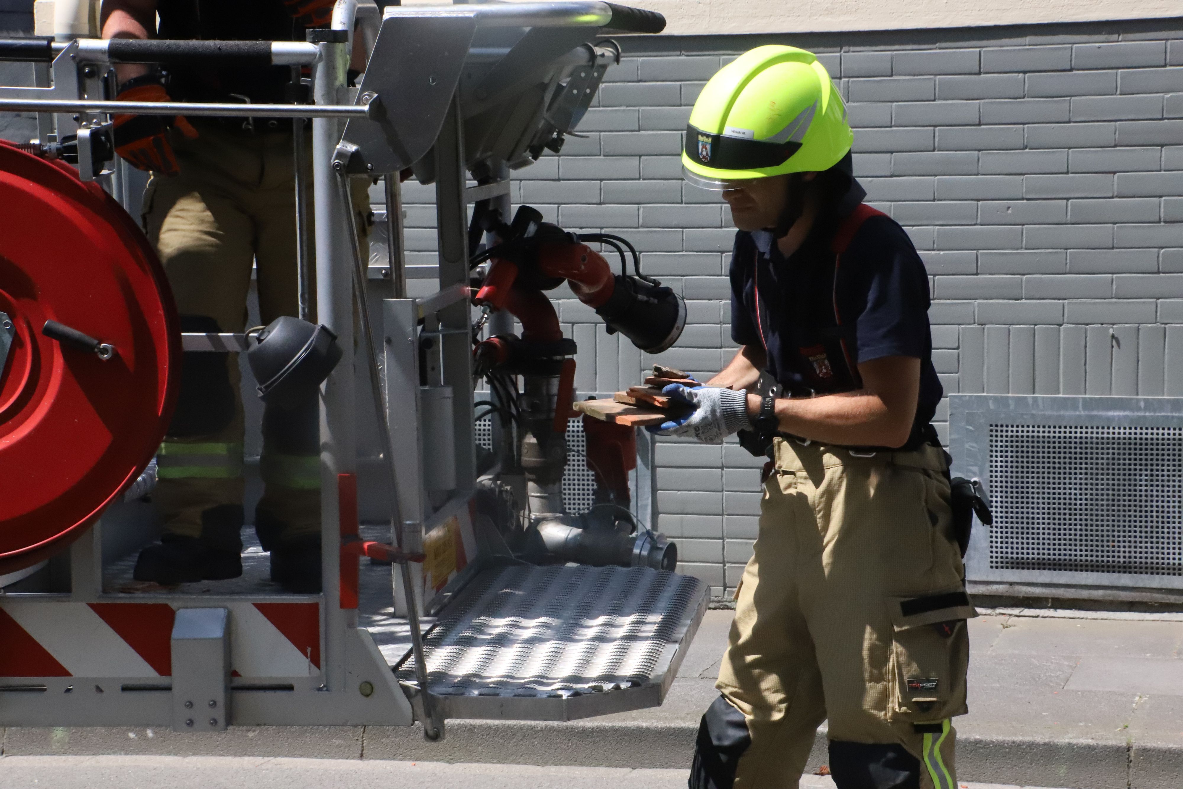 Ein Feuerwehrmann hat kaputte Dachziegel und Mörtel in den Händen.