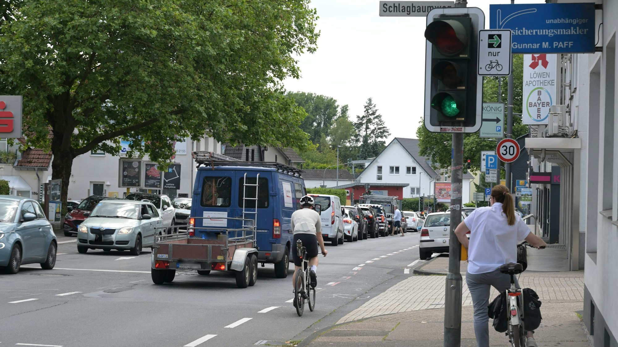 An der Kreuzung steht eine Radfahrerin. Auf der Altenberger-Dom-Straße staut sich der Verkehr.