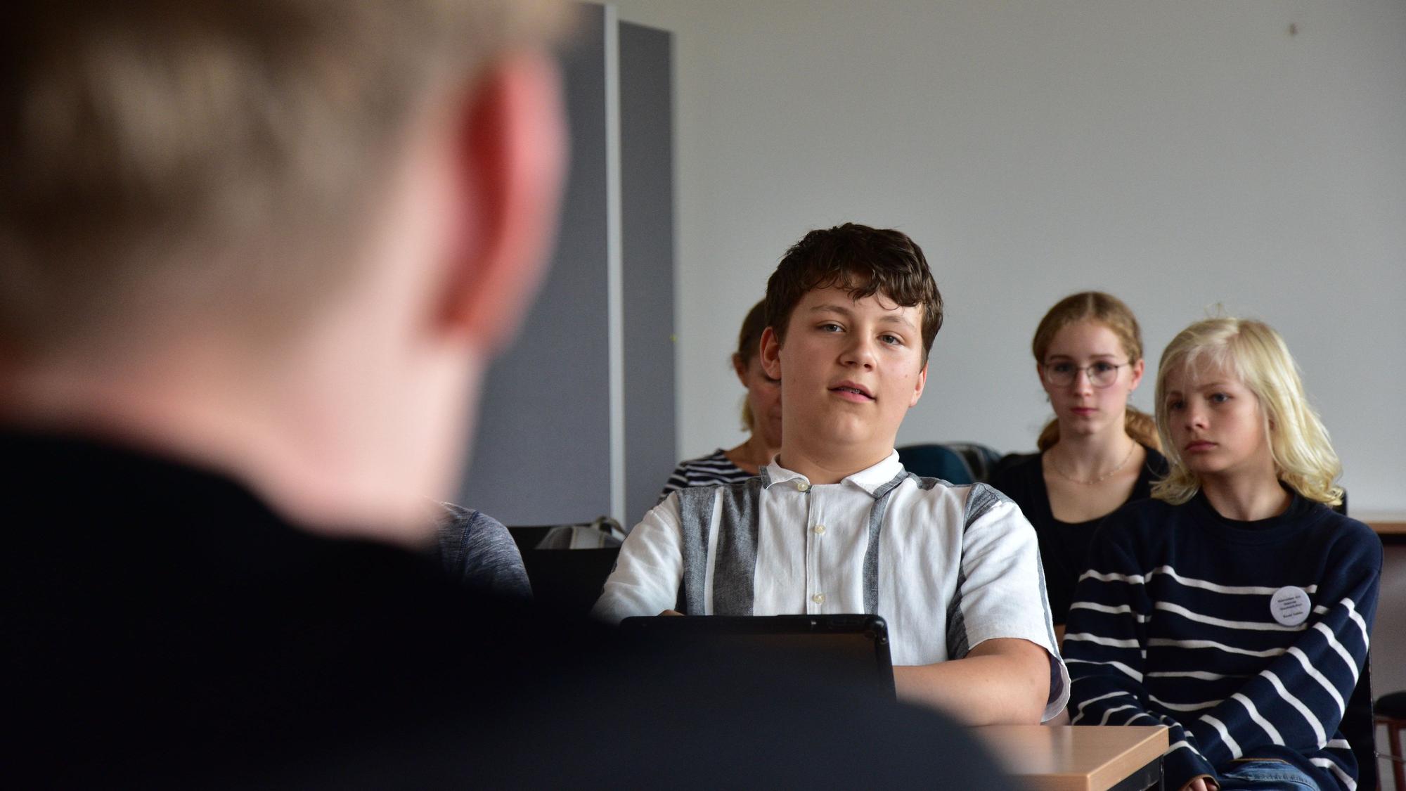 Mehrere Schüler sitzen in einer Klasse.