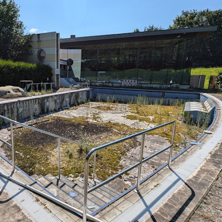 Das Foto zeigt das leere Solebecken hinter dem Familienbad De Bütt, das seit über zehn Jahren verfällt.