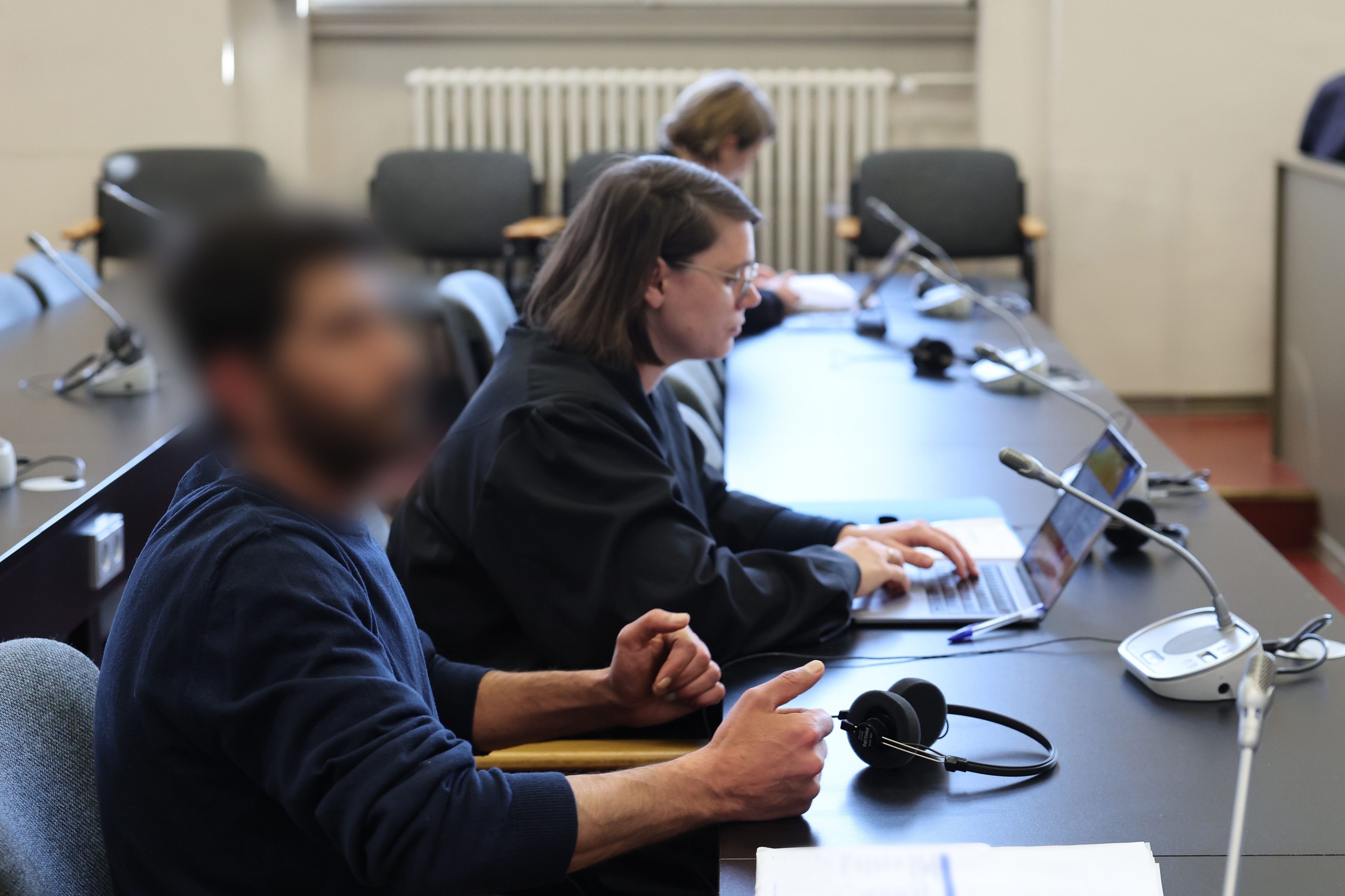 Der Angeklagte  und seine Rechtsanwältin Anna Carlotta Bloch sitzen kurz vor Beginn der Verhandlung in einem Gerichtssaal des Strafjustizgebäudes in Hamburg.