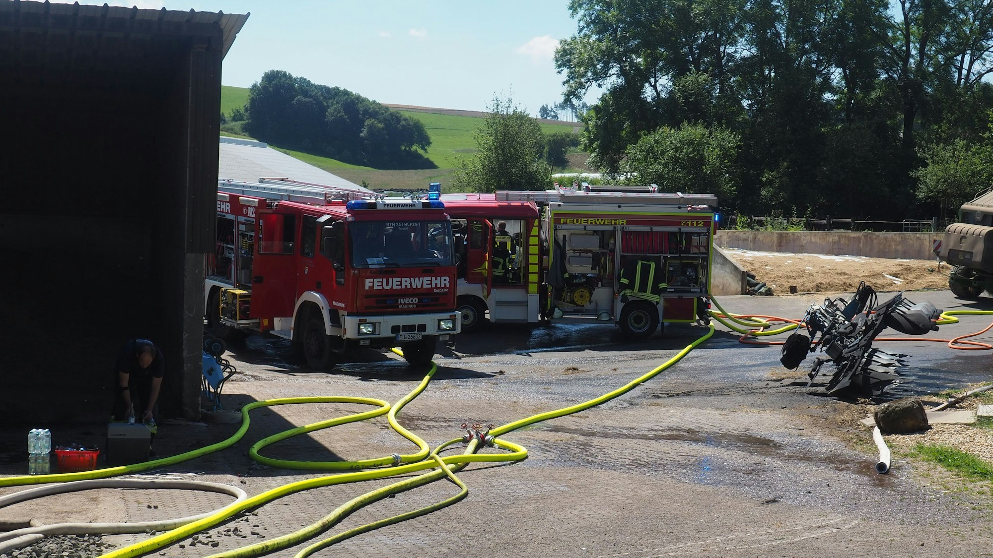 Neben dem Stallgebäude stehen Feuerwehrautos.