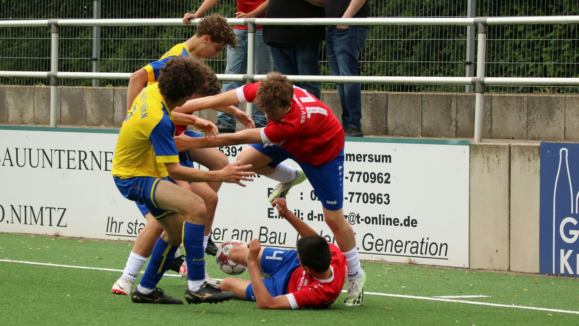 Mit beiden Armen schubst ein Lommersumer Spieler seinen Gegenspieler und springt über einen Mitspieler hinweg.