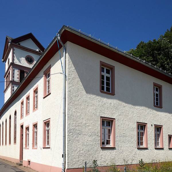 Im Vordergrund ist das Alte Pfarrhaus an der evangelischen Kirche in Hellenthal zu sehen, dahinter lugt der Kirchturm hervor.